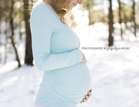 pregnant woman in warm winter clothes standing outside on a snowy